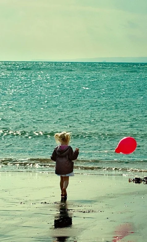 海边拿着红气球的可爱小女孩手机壁纸