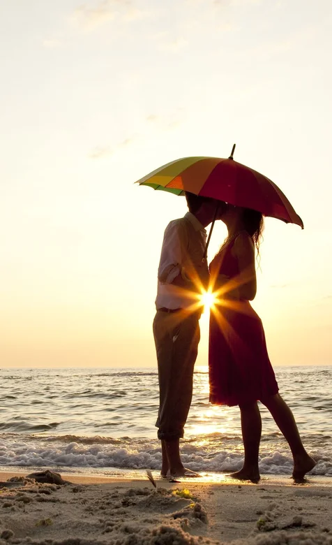 沙滩伞下亲吻的情侣