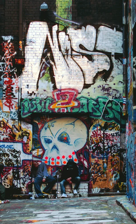 欧美街头布满涂鸦的小巷坐着的年轻人手机壁纸