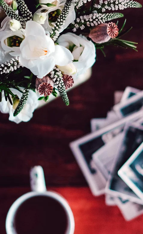 桌上盆栽边上的一杯咖啡和一堆照片的创意手机壁纸