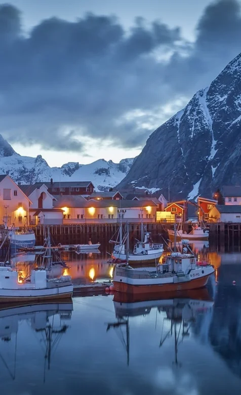 寒冷的雪山地带，山下小镇亮起灯光的欧式建筑和湖中的小船手机壁纸