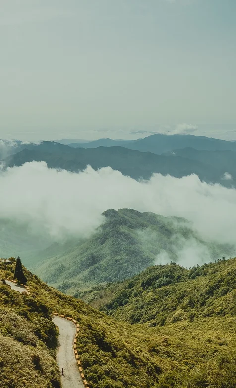 云海围绕的绿色大山，大山间的公路风景手机壁纸