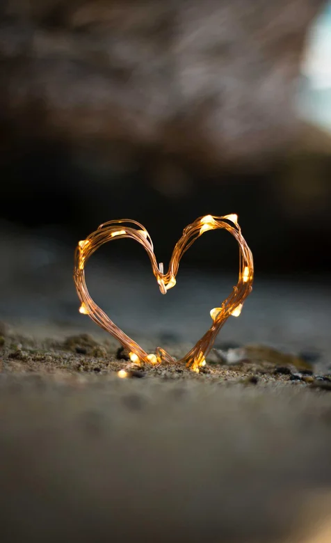 用LED灯带线捏成的爱心插在沙子上的手机壁纸