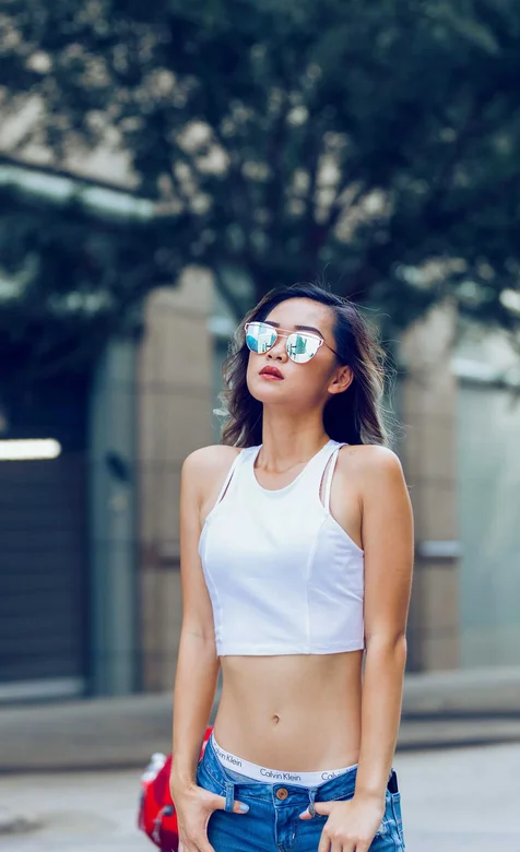 牛仔裤露脐装，戴太阳眼镜的时尚美女街拍