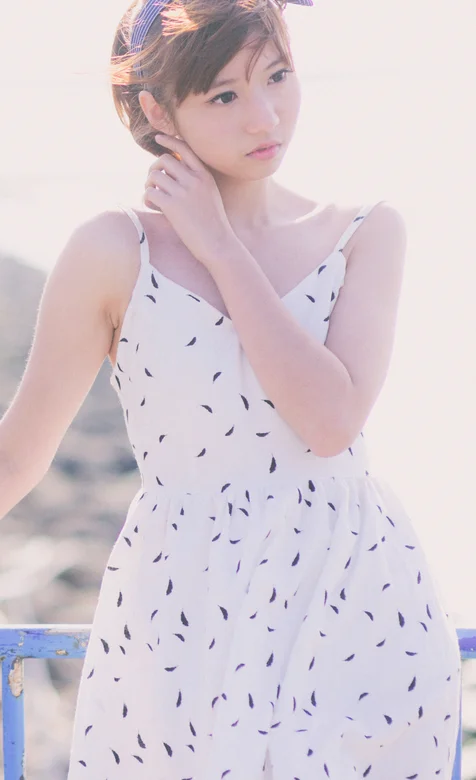 头戴蝴蝶结发带身穿吊带连衣裙的短发美女海边写真