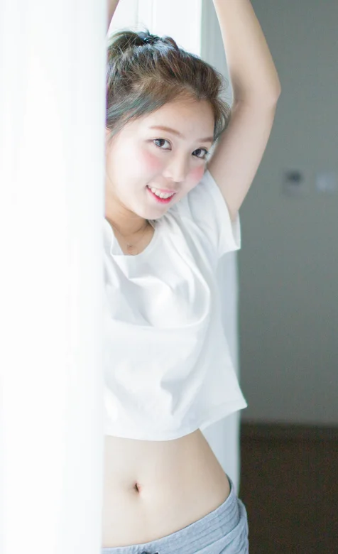 站在窗台窗帘前的可爱露脐装美女